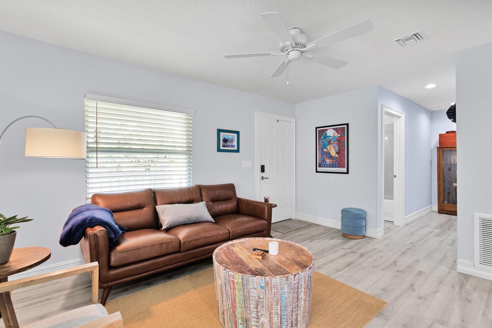 A living room features a brown leather sofa, round wooden coffee table, and light flooring — FELLSMERE, FL