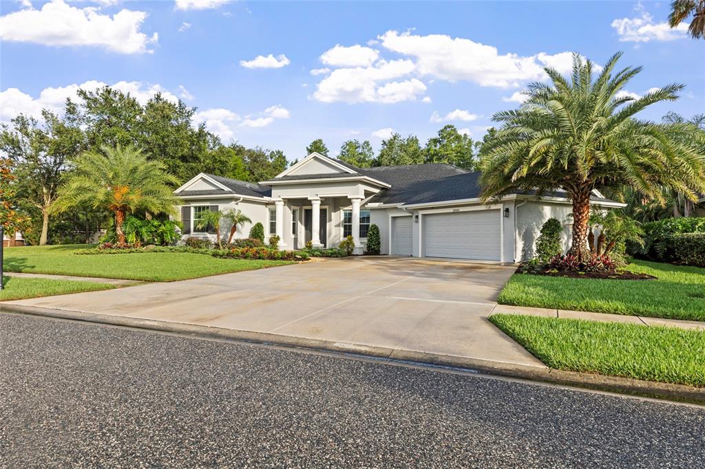 A single-story house with a gray exterior, a three-car garage, and palm trees — 20454 LACE CASCADE RD, LAND O LAKES, FL