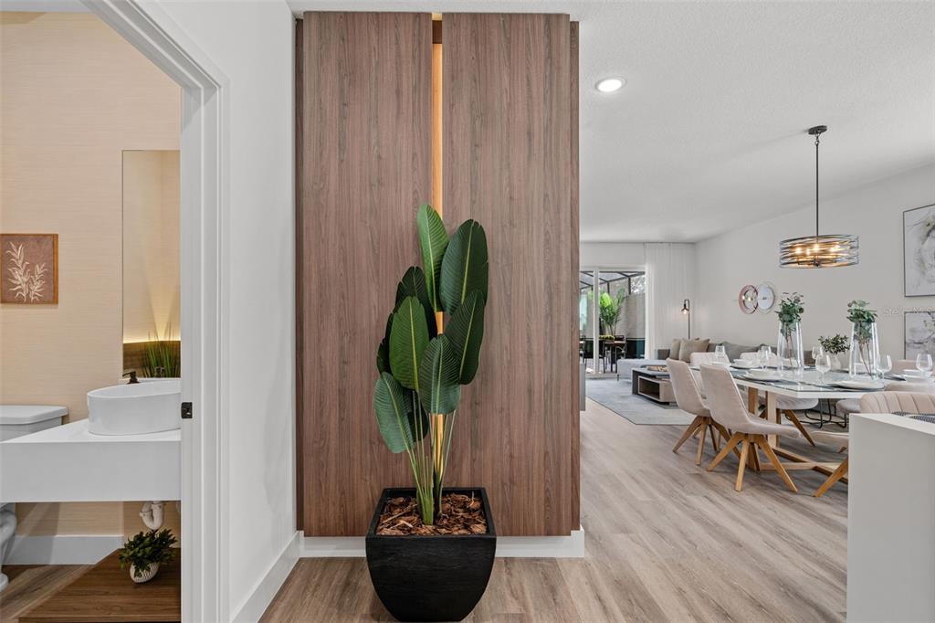 A wood-paneled accent wall with a potted plant separates a bathroom from a dining area — 9084 BORACAY COURT, KISSIMMEE, FL