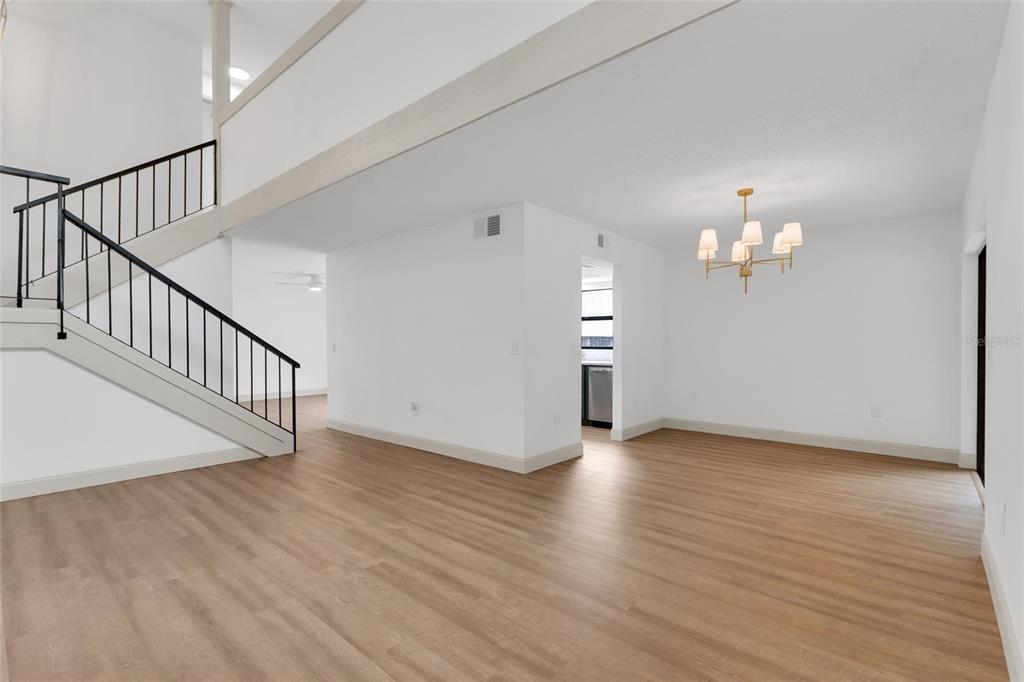 An open-concept dining area with light wood flooring, a chandelier, and a staircase — 3948 ORCHARD HILL CIRCLE, PALM HARBOR, FL