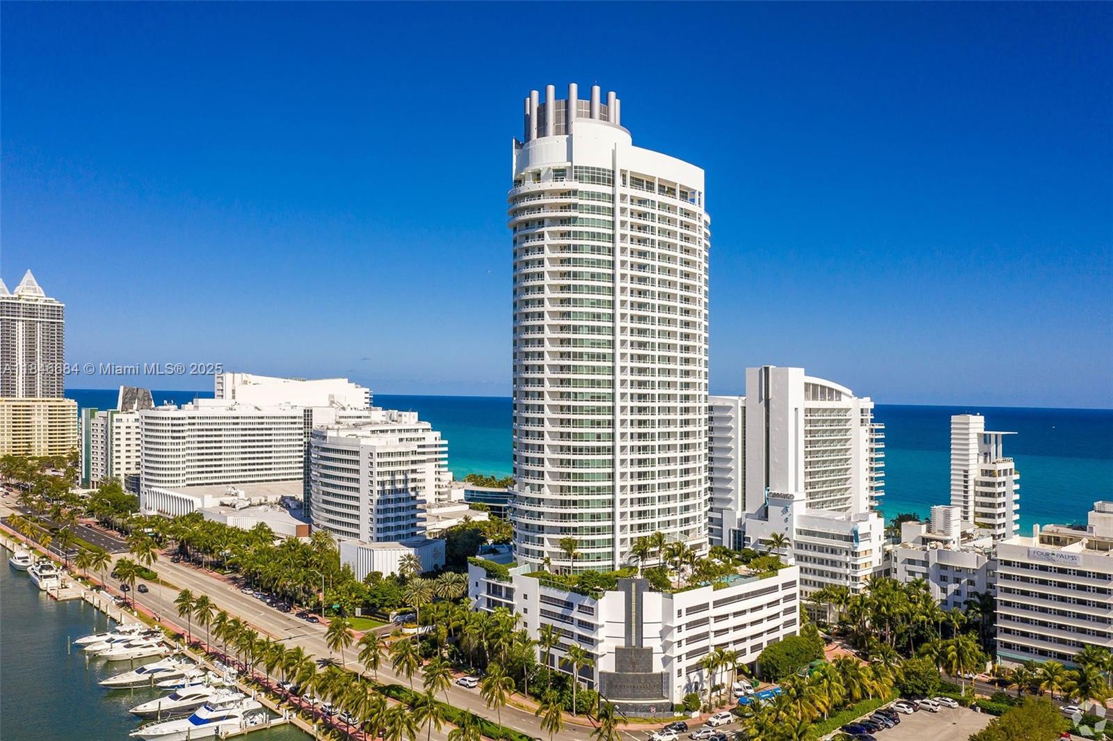 An aerial view of a tall, cylindrical white skyscraper surrounded by other buildings and boats — 4401 Collins Ave, Miami Beach FL 33140, MIAMI BEACH, FL