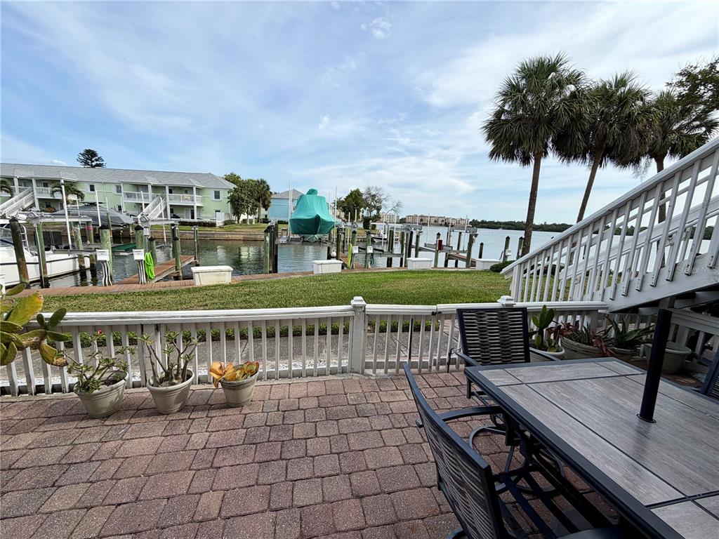 A patio with a dining set overlooks a grassy lawn, boat docks, and a waterway — 5009 STARFISH DRIVE SE UNIT A, ST PETERSBURG, FL