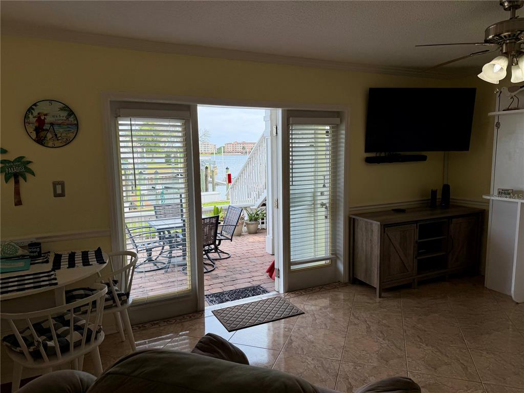A living room with tile floors, a wall-mounted television, and sliding doors opening to a patio — 5009 STARFISH DRIVE SE UNIT A, ST PETERSBURG, FL
