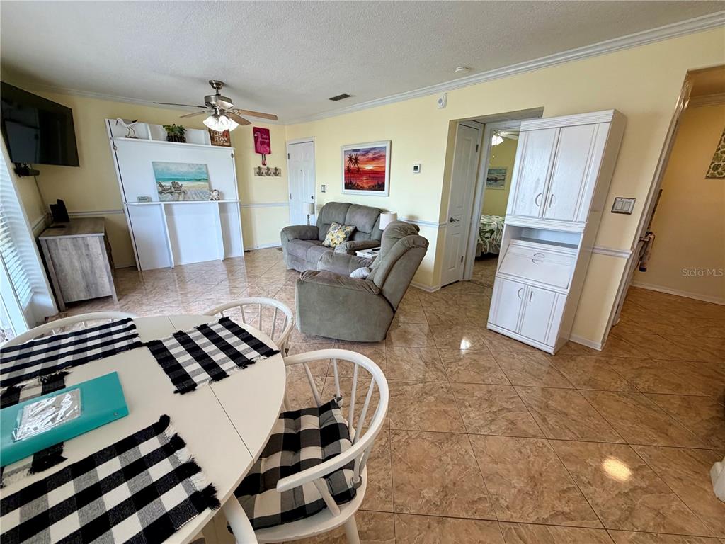 A living room features tile flooring, a beige sofa, a white cabinet, and a dining area — 5009 STARFISH DRIVE SE UNIT A, ST PETERSBURG, FL