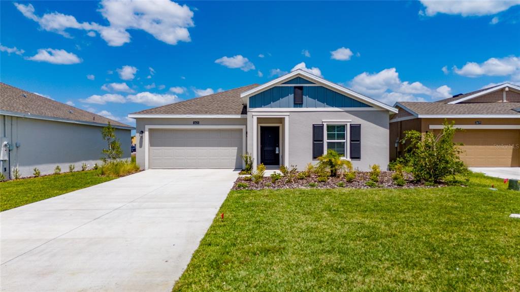 A single-story house with a gray stucco exterior, blue gable accent, and a concrete driveway — 5625 LE MARIN WAY, KISSIMMEE, FL