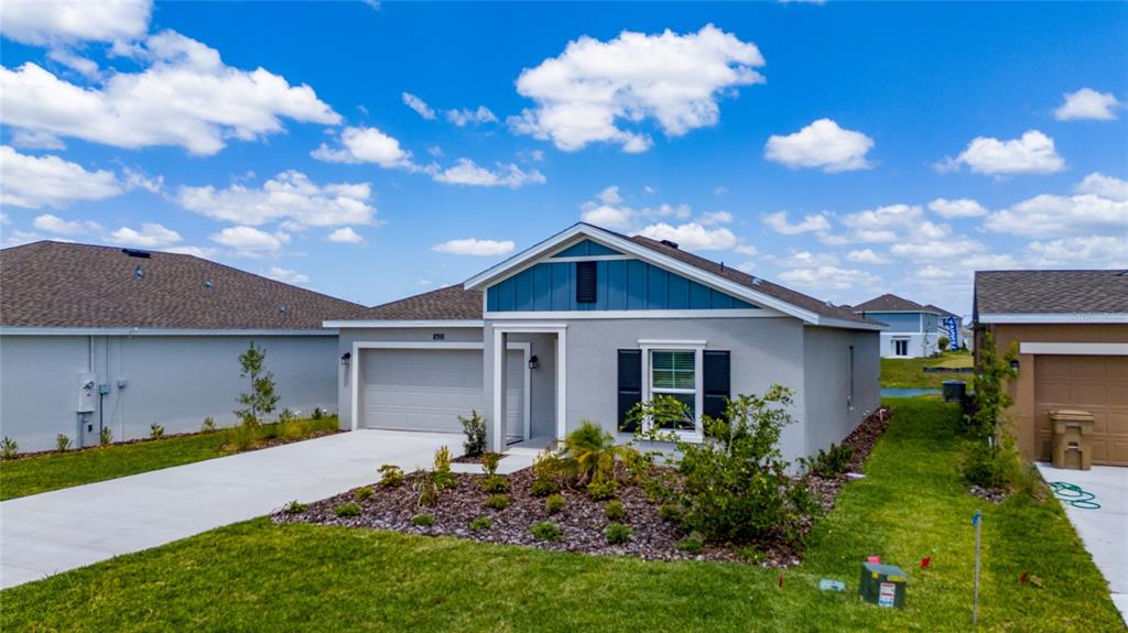 A single-story house with a gray stucco exterior, blue gable siding, and a concrete driveway — 5625 LE MARIN WAY, KISSIMMEE, FL
