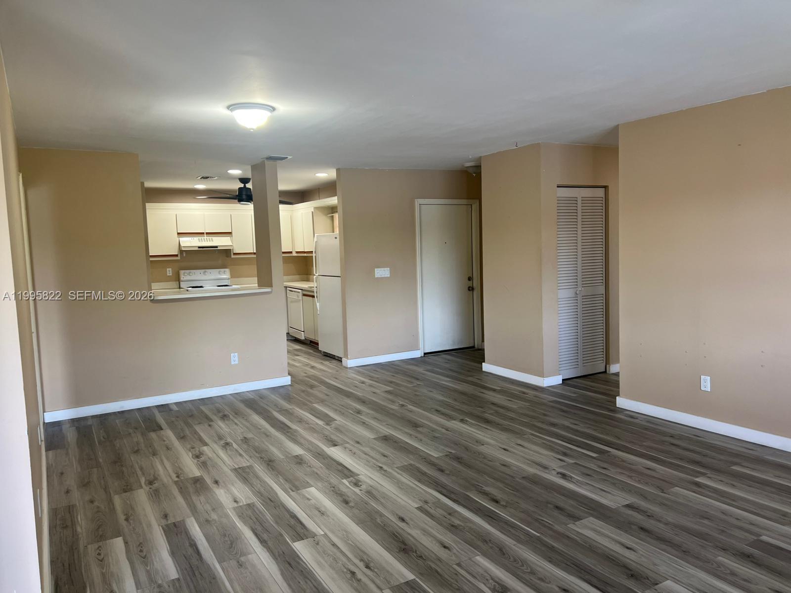 An open-concept living area features light brown walls, gray wood-look flooring, and a kitchen pass-through — 3655 NW 94th Ave # 8H, Sunrise FL 33351, SUNRISE, FL
