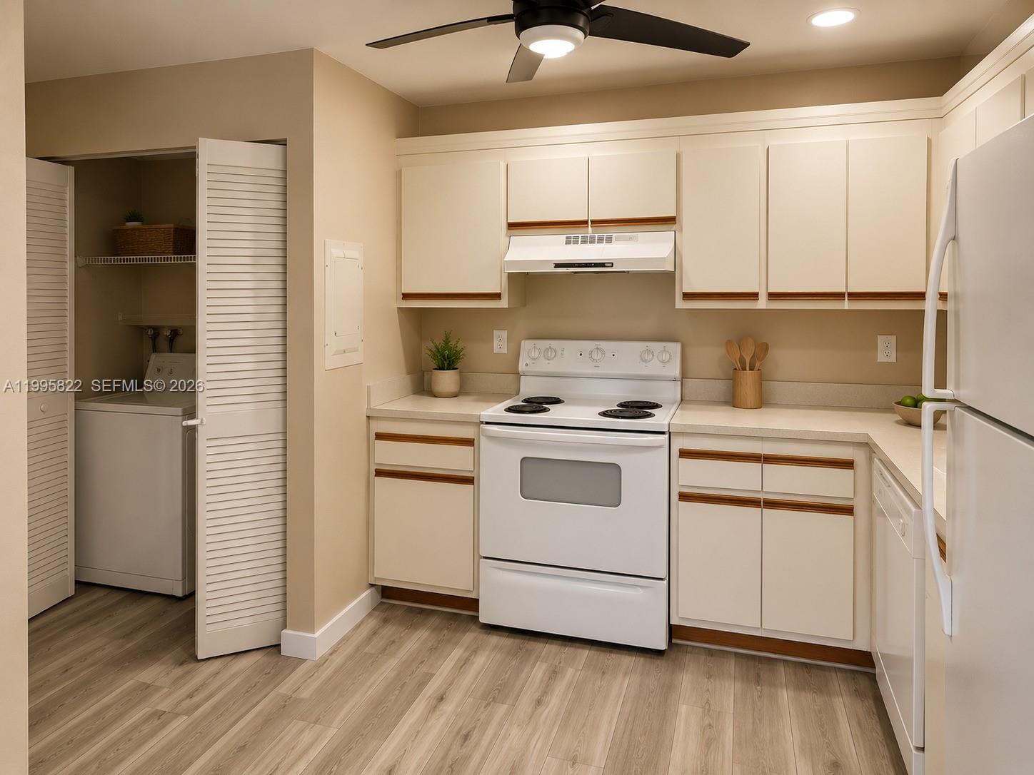 A kitchen features white cabinets with wood trim, white appliances, and light wood-look flooring — 3655 NW 94th Ave # 8H, Sunrise FL 33351, SUNRISE, FL