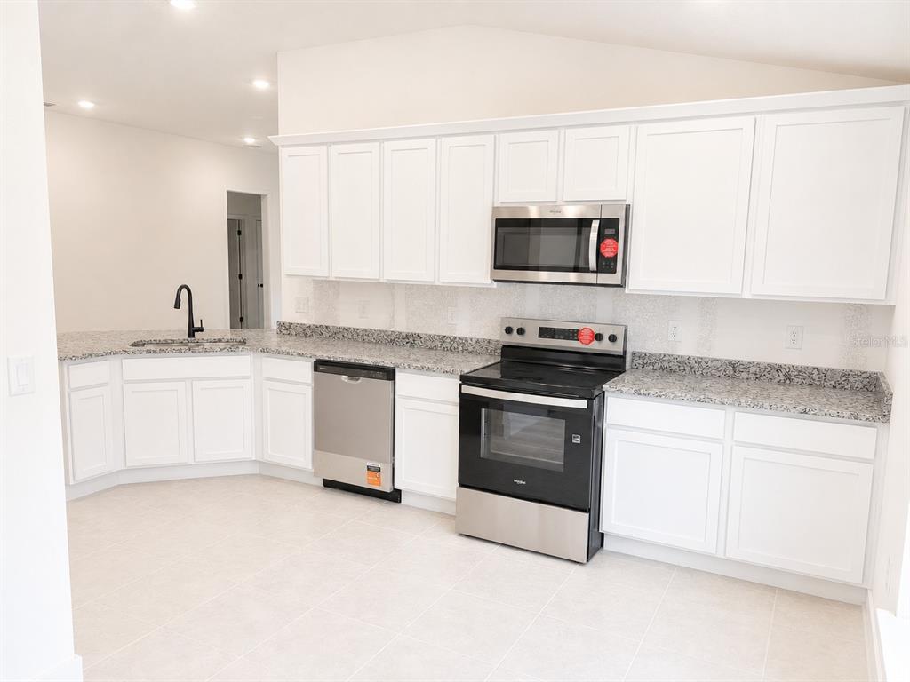 A kitchen with white cabinets, granite countertops, and stainless steel appliances — 1639 ANN ROSE WAY, LEESBURG, FL
