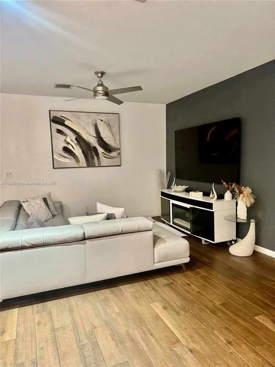 A living room features a grey sectional sofa, a wall-mounted television, and a media console — 4039 NW 11th St, Lauderhill FL 33313, LAUDERHILL, FL