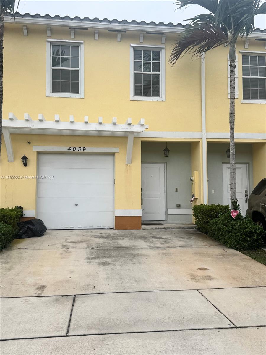 A yellow two-story townhouse features a single-car garage and a small front entrance — 4039 NW 11th St, Lauderhill FL 33313, LAUDERHILL, FL