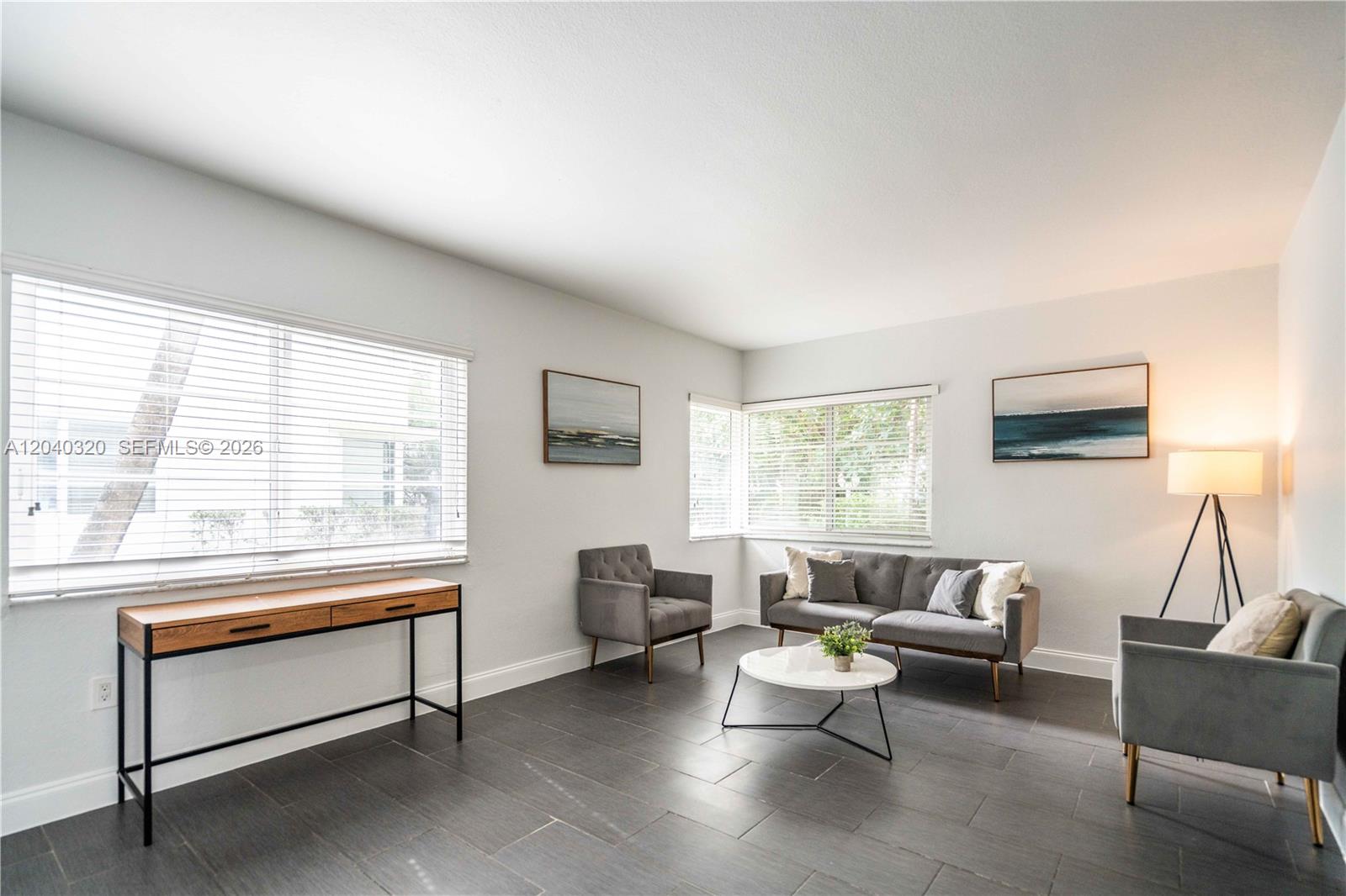 A living room features gray tile floors, a sofa, two armchairs, and a console table — 1007 Bay Dr # 104, Miami Beach FL 33141, MIAMI BEACH, FL