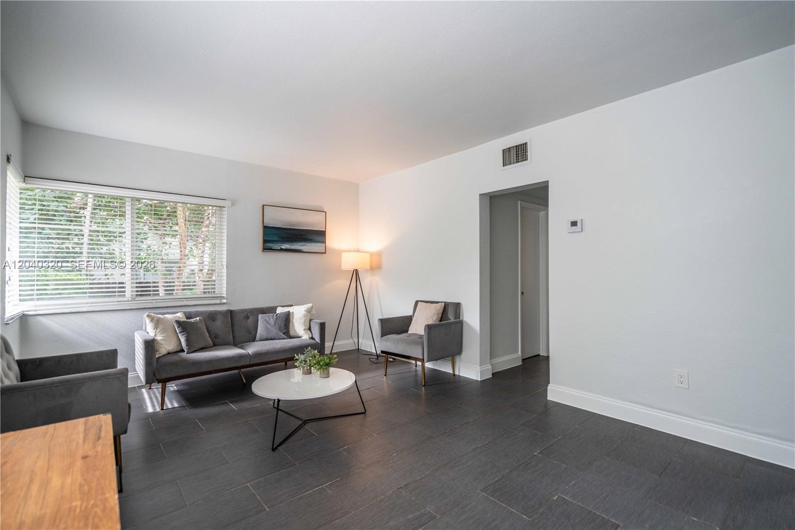 A living room features gray furniture, a white coffee table, and dark tile flooring — 1007 Bay Dr # 104, Miami Beach FL 33141, MIAMI BEACH, FL