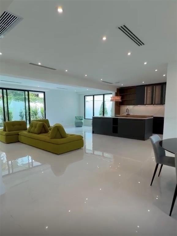 A modern open-concept living area features a green sofa, a dark kitchen island, and tile floors — D1 SUN VALLEY, GUAYNABO, PR