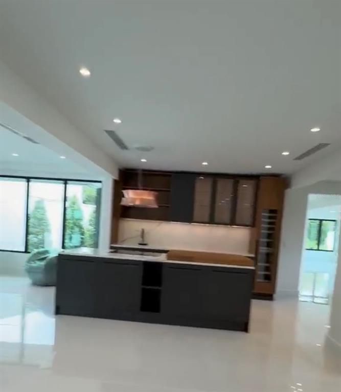 A modern kitchen features a dark island, wood-toned cabinetry, and white tile flooring — D1 SUN VALLEY, GUAYNABO, PR