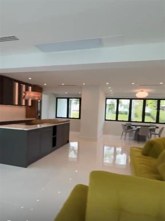A modern open-concept kitchen and dining area features dark cabinetry, a kitchen island, and tile flooring — D1 SUN VALLEY, GUAYNABO, PR