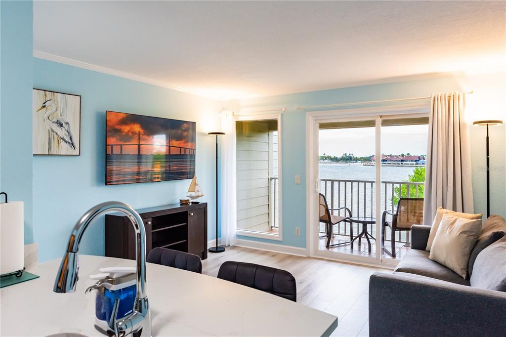 A living room with light blue walls, a balcony overlooking water, and a kitchen island — 2506 N ROCKY POINT DRIVE UNIT 275, TAMPA, FL