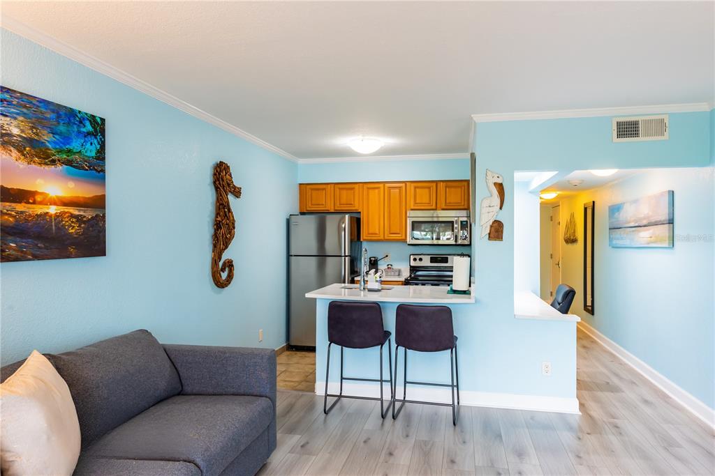 A small kitchen with wood cabinets and stainless steel appliances overlooks a living area — 2506 N ROCKY POINT DRIVE UNIT 275, TAMPA, FL