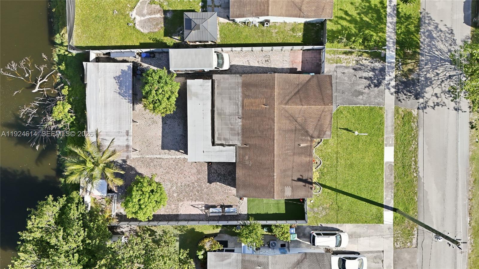 An aerial view shows a house with a large backyard, patio, and waterfront access — 2211 NW 46th Ave, Lauderhill FL 33313, LAUDERHILL, FL