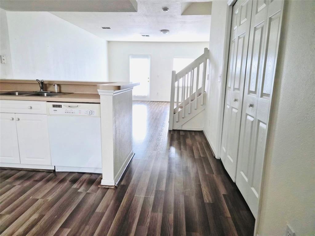 A kitchen with white cabinets and a dishwasher overlooks a living area with stairs — 4352 HAR PAUL CIRCLE, TAMPA, FL