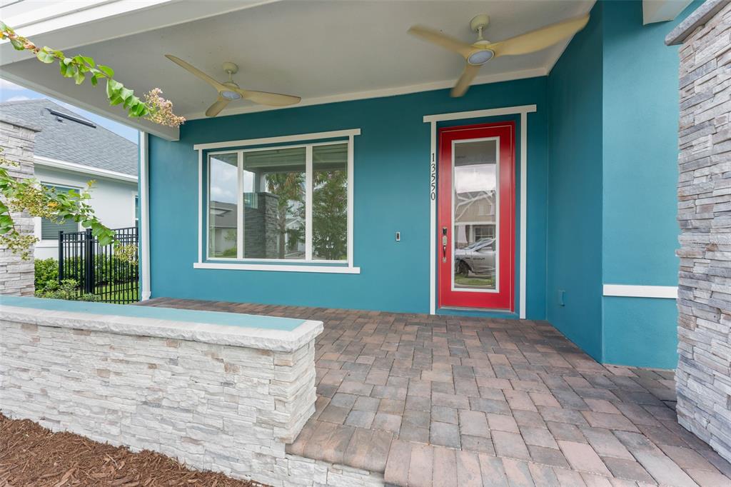 A covered front porch features teal walls, a red front door, and stone pillar accents — 13550 MCMILLAN DRIVE, ORLANDO, FL