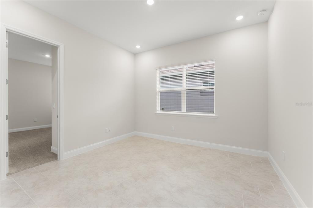 A bright, empty room with light tile flooring, white walls, and a glass-paneled entry door — 13550 MCMILLAN DRIVE, ORLANDO, FL