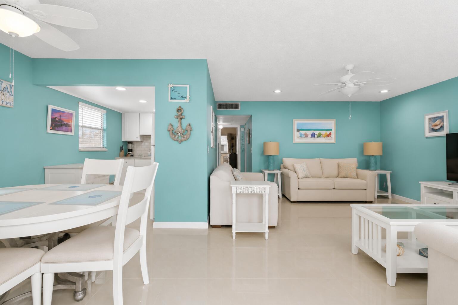 A bright living and dining area features teal walls, white furniture, and tile flooring — 520 Monaco K, Delray Beach FL 33446, DELRAY BEACH, FL