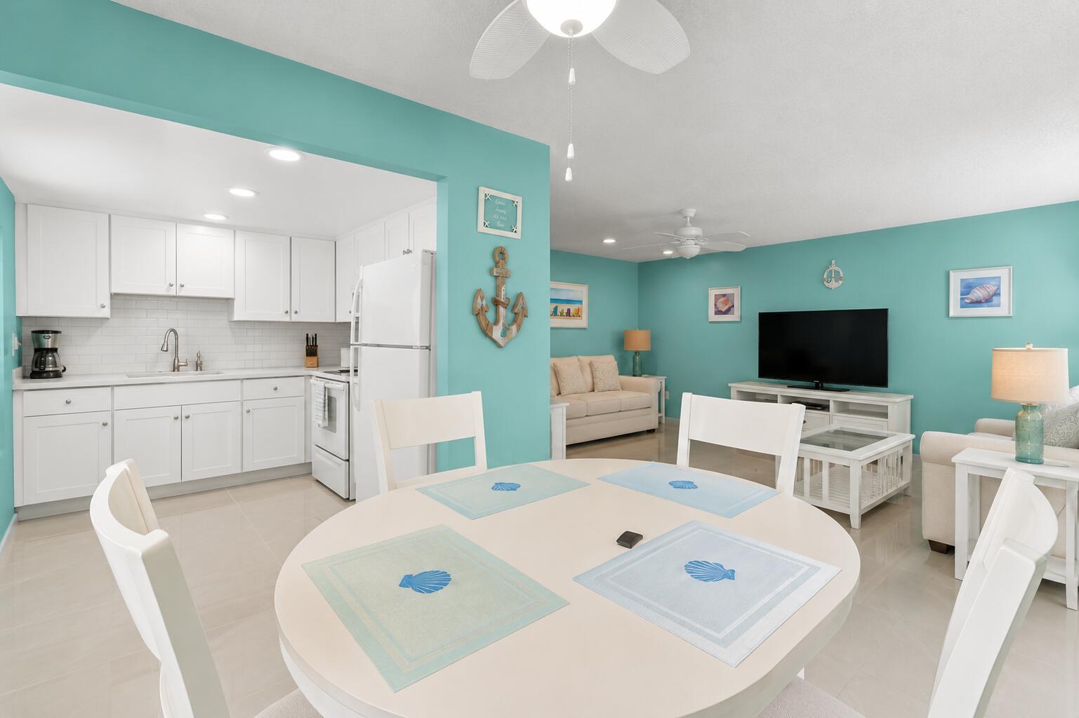 A dining area with a round table sits before a white kitchen and living room — 520 Monaco K, Delray Beach FL 33446, DELRAY BEACH, FL