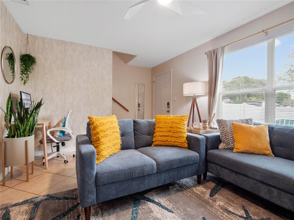 A living room features a blue sofa, yellow pillows, a desk, and a large window — 218 CANAVERAL BEACH BOULEVARD, CAPE CANAVERAL, FL