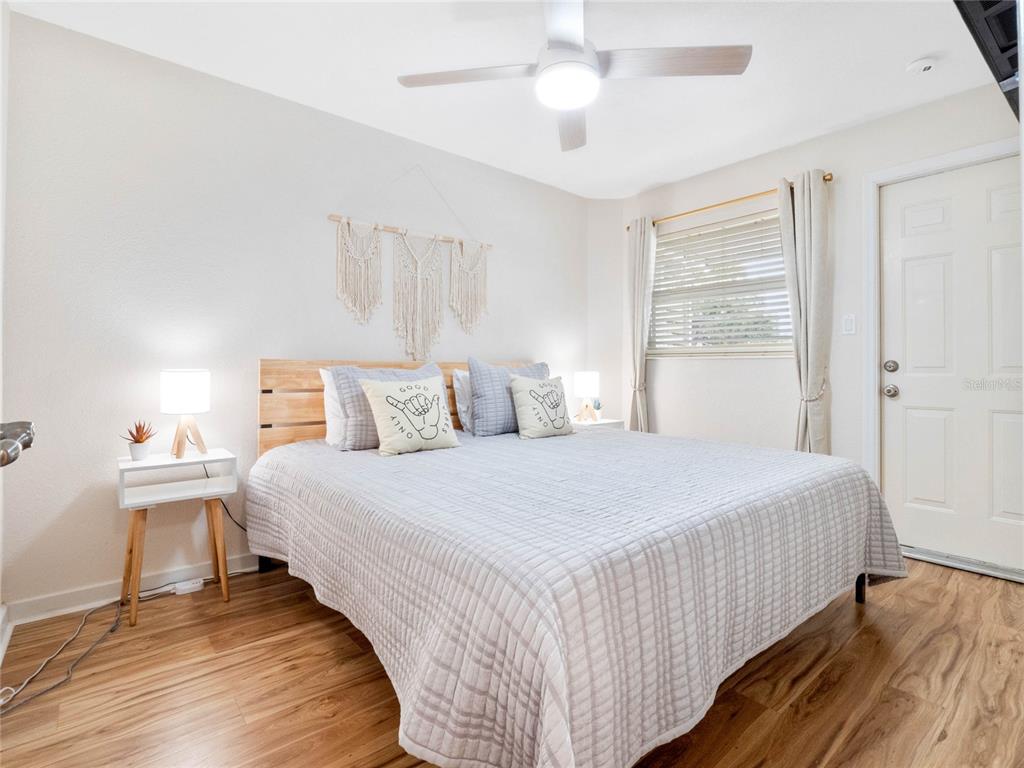 A bedroom with a bed, light wood flooring, a ceiling fan, and a window with curtains — 218 CANAVERAL BEACH BOULEVARD, CAPE CANAVERAL, FL
