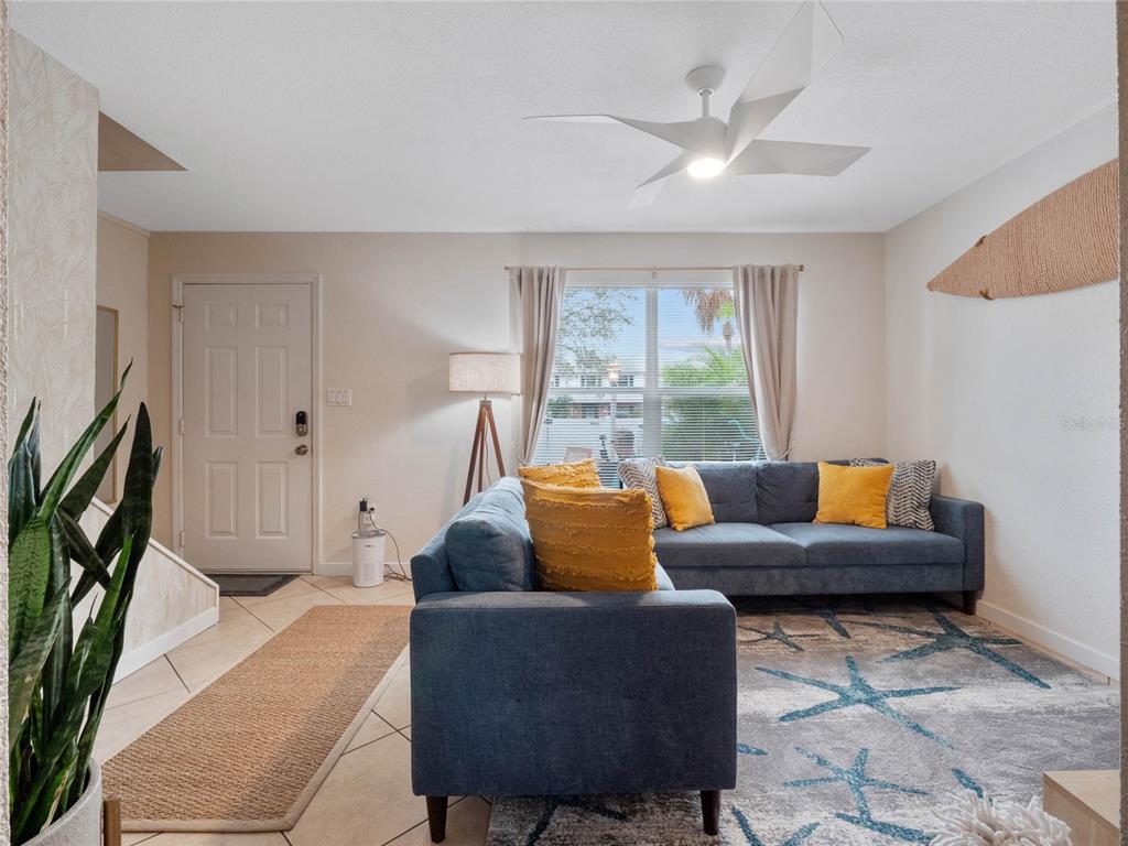 A living room features a blue sectional sofa, a patterned rug, and a ceiling fan — 218 CANAVERAL BEACH BOULEVARD, CAPE CANAVERAL, FL