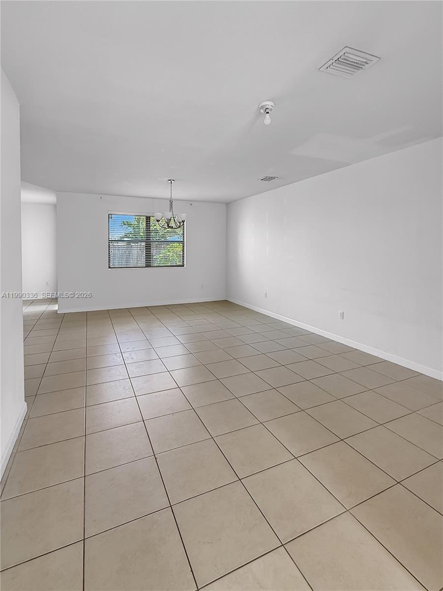 An empty room features beige tile flooring, white walls, and a single window — 709 SE 35th Ave, Homestead FL 33033, HOMESTEAD, FL