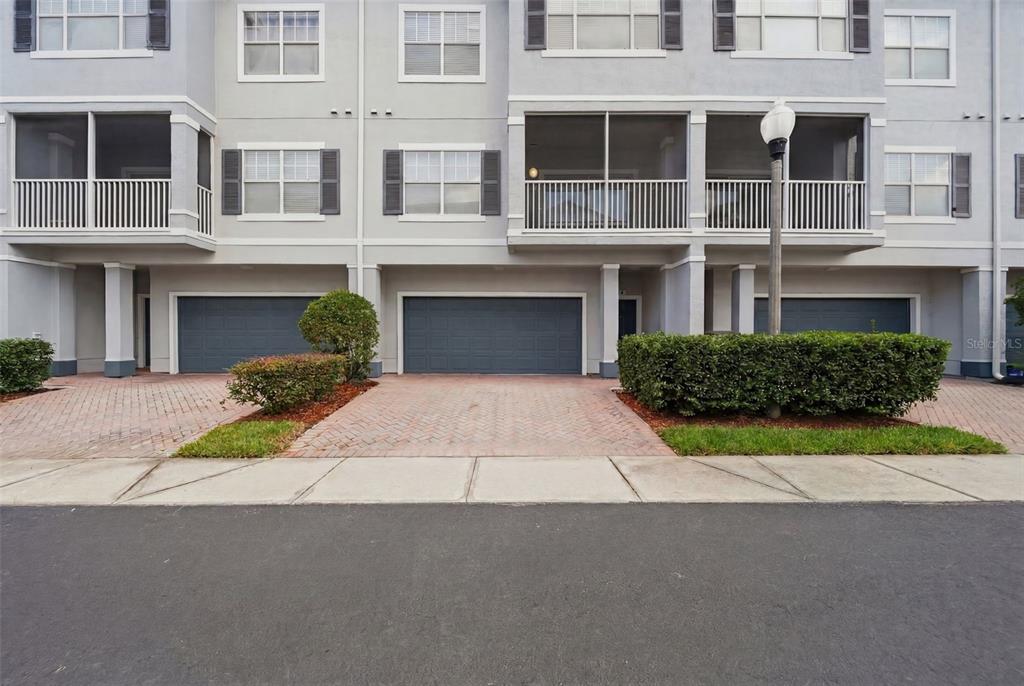 The exterior view shows a multi-story townhouse with three garage doors and screened balconies — 2532 GRAND CENTRAL PARKWAY UNIT 8, ORLANDO, FL
