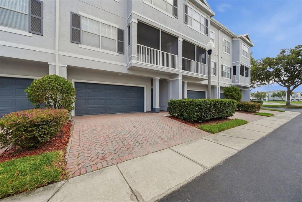 A multi-story townhouse exterior features a brick driveway, a garage, and a screened balcony — 2532 GRAND CENTRAL PARKWAY UNIT 8, ORLANDO, FL