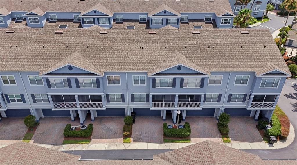 An aerial view of a multi-story blue townhouse complex with paved driveways and shingled roofs — 2532 GRAND CENTRAL PARKWAY UNIT 8, ORLANDO, FL