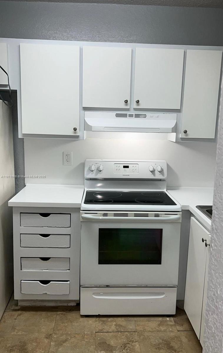 A kitchen features white cabinets, a white electric stove, and a stack of four drawers — 575 W 69th St # 208, Hialeah FL 33014, HIALEAH, FL