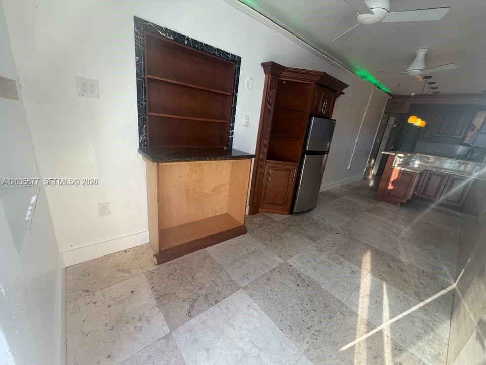 A kitchen area features tile flooring, a built-in wooden shelving unit, and a stainless refrigerator — HOLLYWOOD, FL
