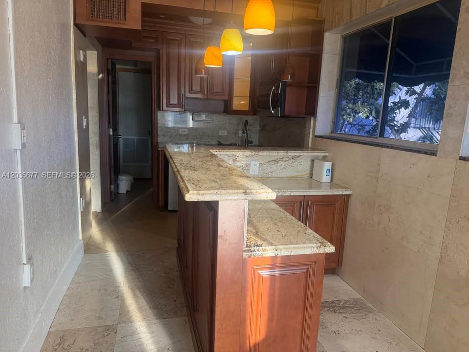 A kitchen features wood cabinets, granite countertops, a breakfast bar, and tile flooring — HOLLYWOOD, FL
