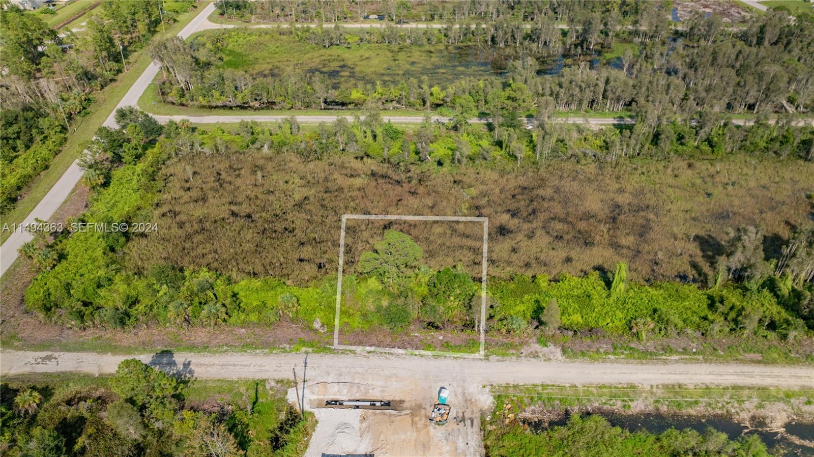 An aerial view shows a rectangular plot of land outlined in white amidst vegetation — 853 Belden Ave, Lehigh Acres FL 33936, LEHIGH ACRES, FL