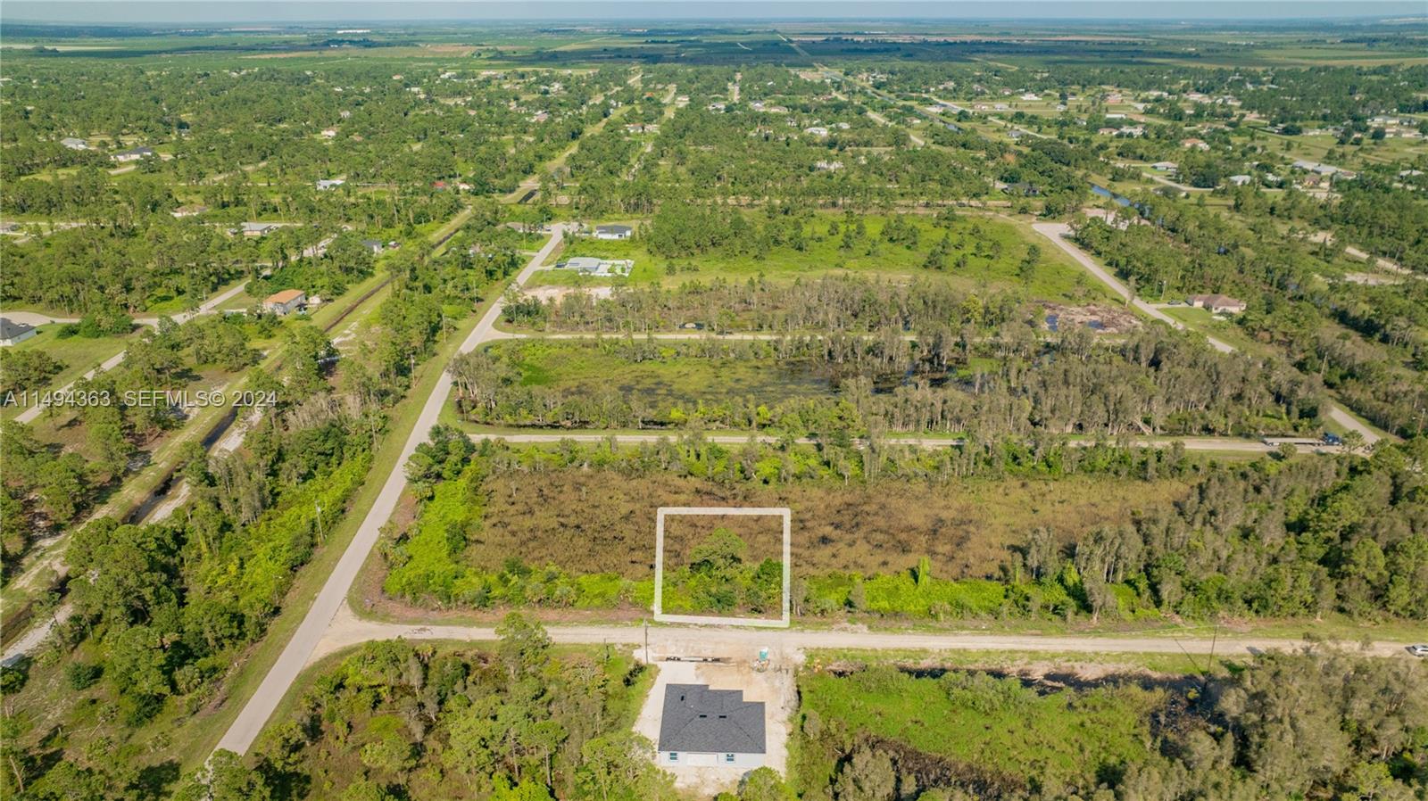 An aerial view shows a rectangular plot of land outlined in white near a house — 853 Belden Ave, Lehigh Acres FL 33936, LEHIGH ACRES, FL