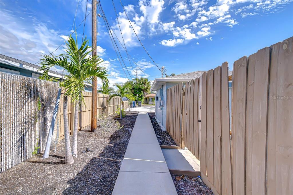 A concrete walkway leads between a wooden fence and a house with palm trees — 4444 17TH STREET W UNIT B, BRADENTON, FL