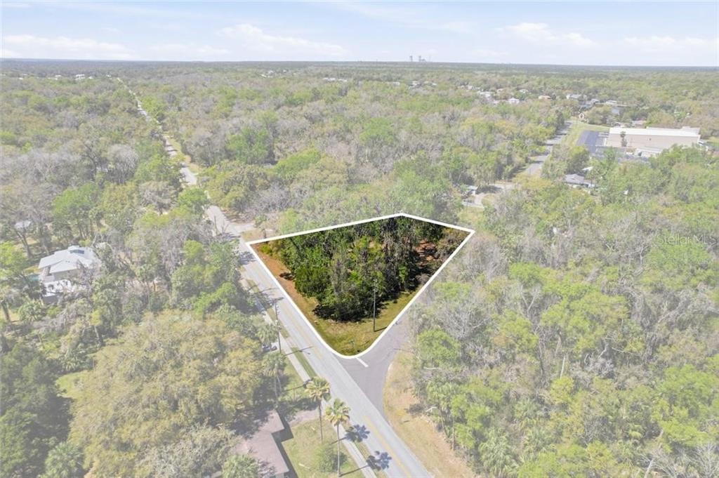 An aerial view shows a triangular, wooded vacant lot situated at a road intersection — 1325 NW 19TH STREET, CRYSTAL RIVER, FL