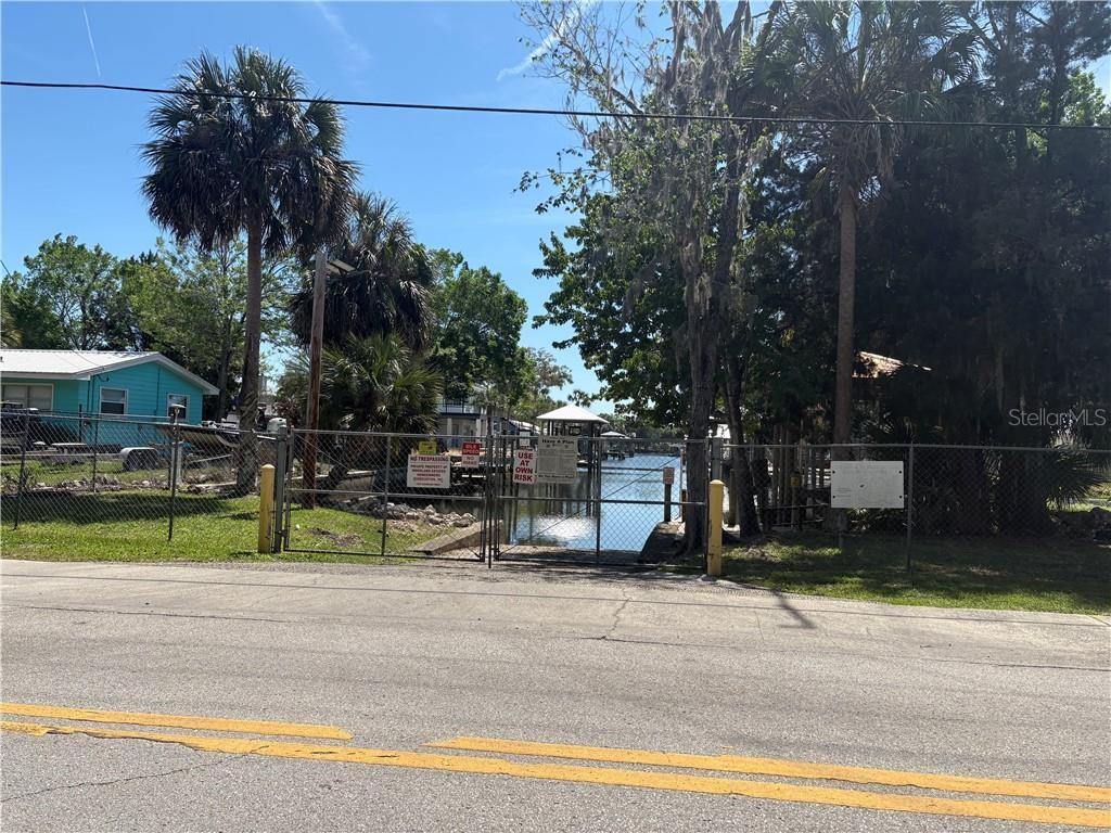 A gated boat ramp leads to a canal between trees and a small house — 1325 NW 19TH STREET, CRYSTAL RIVER, FL