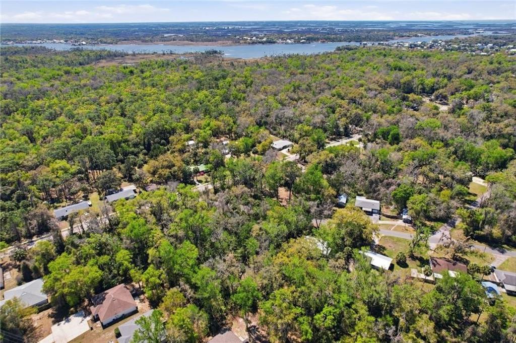 An aerial view shows a residential neighborhood nestled within a dense forest near a body of water — 1325 NW 19TH STREET, CRYSTAL RIVER, FL