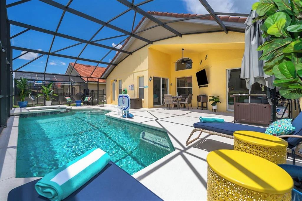 A screened-in patio features a swimming pool, lounge chairs, and outdoor dining area — 136 ROSSO DRIVE, DAVENPORT, FL