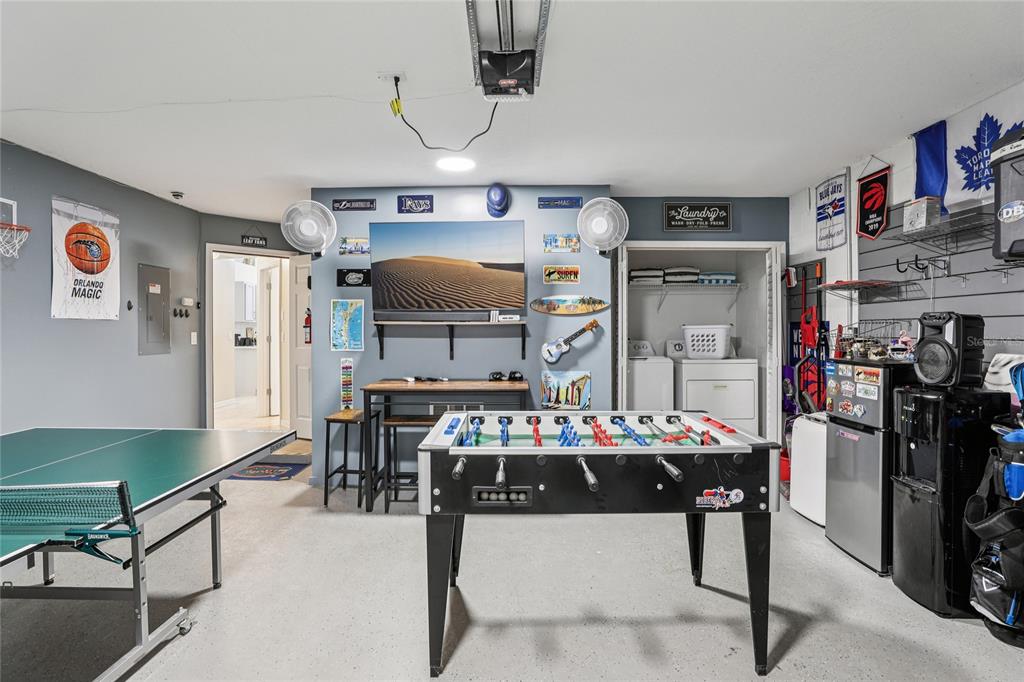 A garage converted into a game room with a foosball table, ping pong table, and laundry — 136 ROSSO DRIVE, DAVENPORT, FL