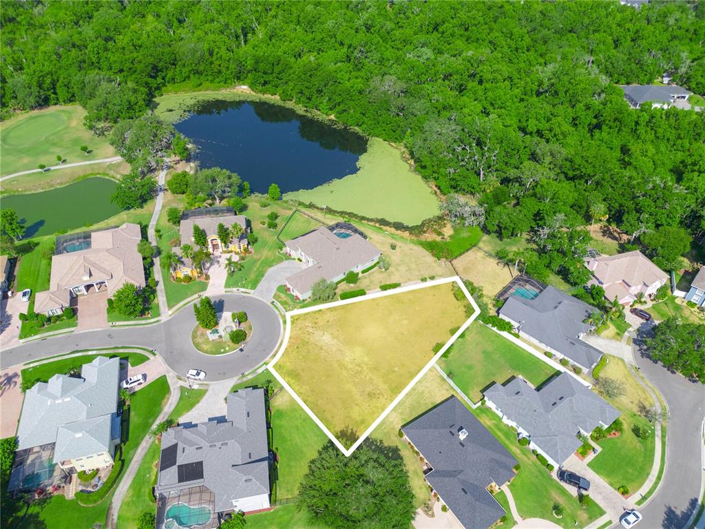 An aerial view shows a vacant residential lot outlined in white within a suburban neighborhood — WHISPER WOODS DRIVE, LAKELAND, FL