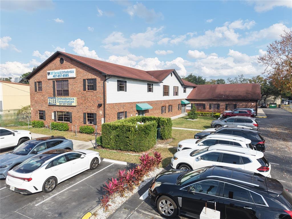 An exterior view of a two-story brick and white siding commercial building with a parking lot — 9753 S ORANGE BLOSSOM TRAIL UNIT 103, ORLANDO, FL