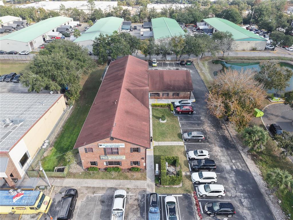 An aerial view shows a brick commercial building with a red roof and parking lot — 9753 S ORANGE BLOSSOM TRAIL UNIT 103, ORLANDO, FL