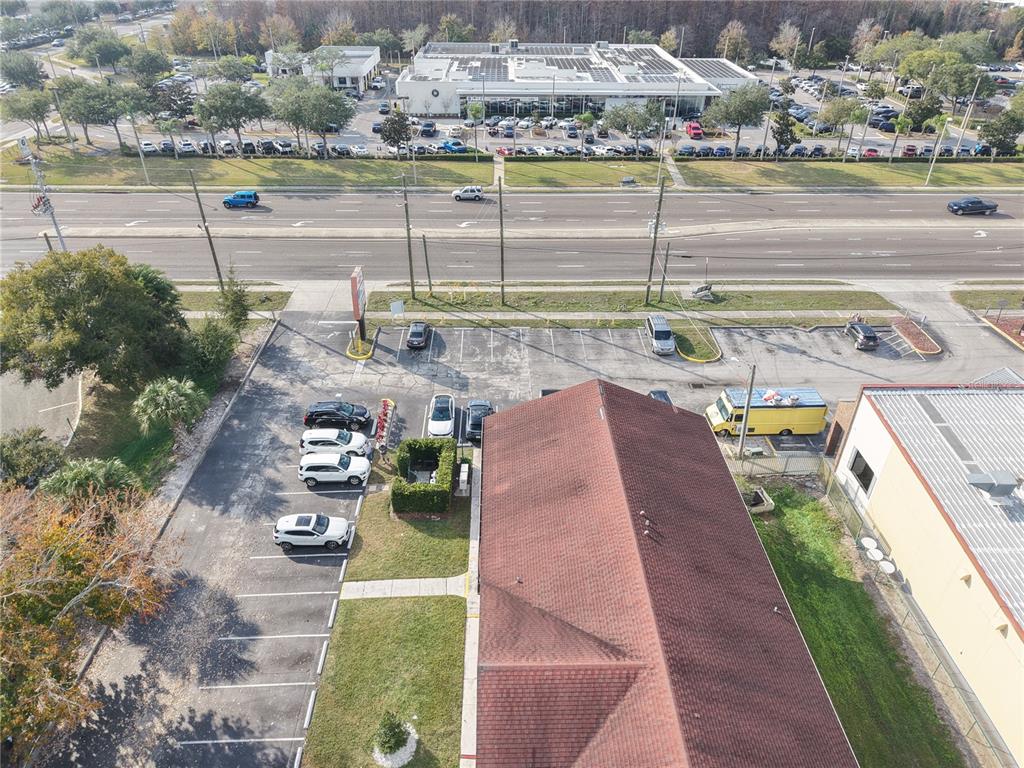 An aerial view shows a commercial building with a red roof and an adjacent parking lot — 9753 S ORANGE BLOSSOM TRAIL UNIT 103, ORLANDO, FL